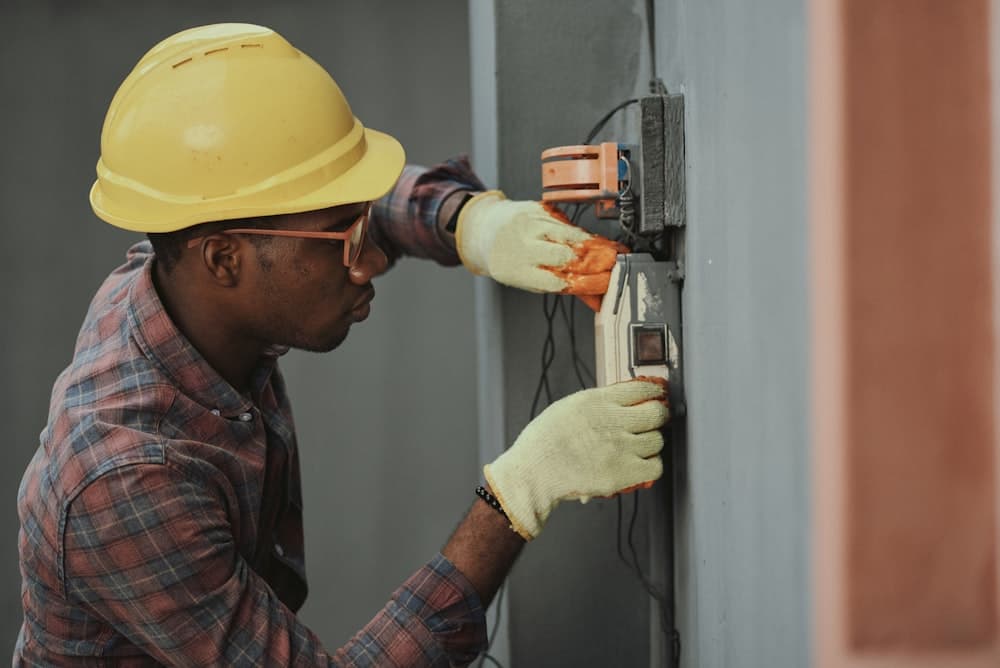 Electrician fitting a wall panel while wearing a hard hat